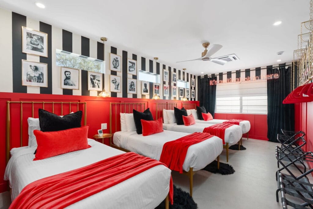 Four beds decorated in white, black and red are set up in a dorm-style bedroom at a bachelorette party pad in Phoenix