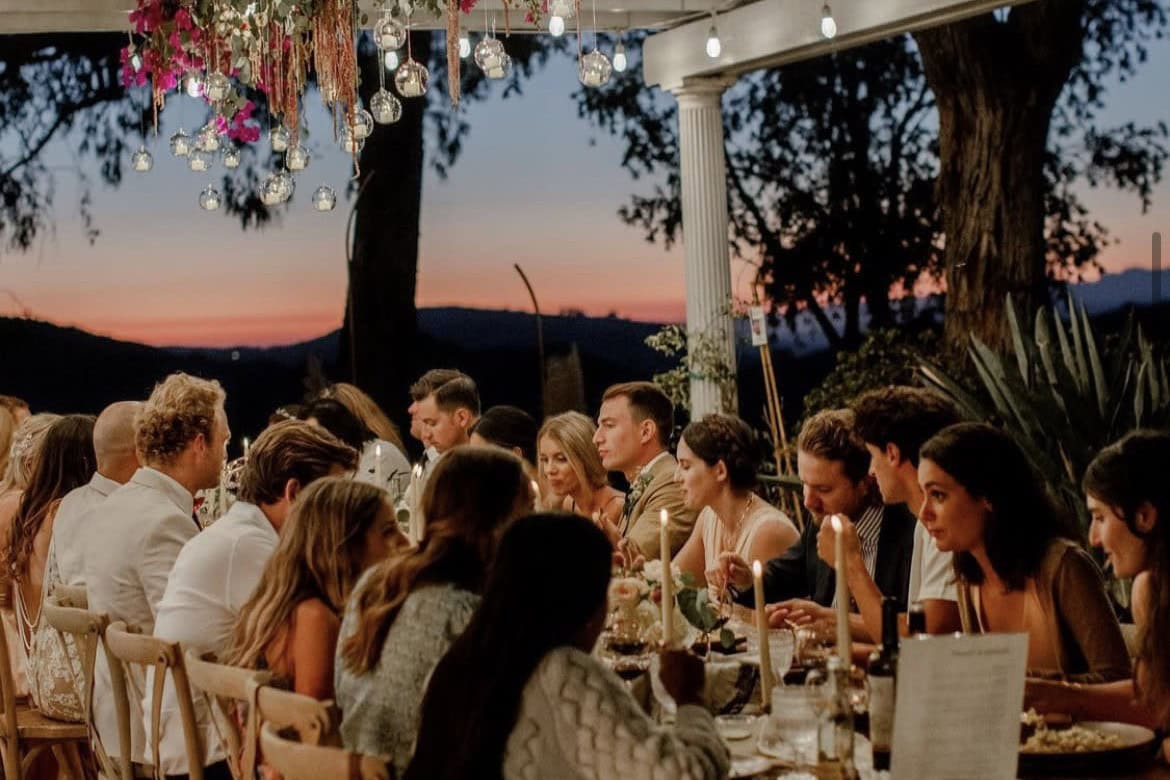 Outdoor Georgia wedding dinner under pergola with hanging florals at sunset