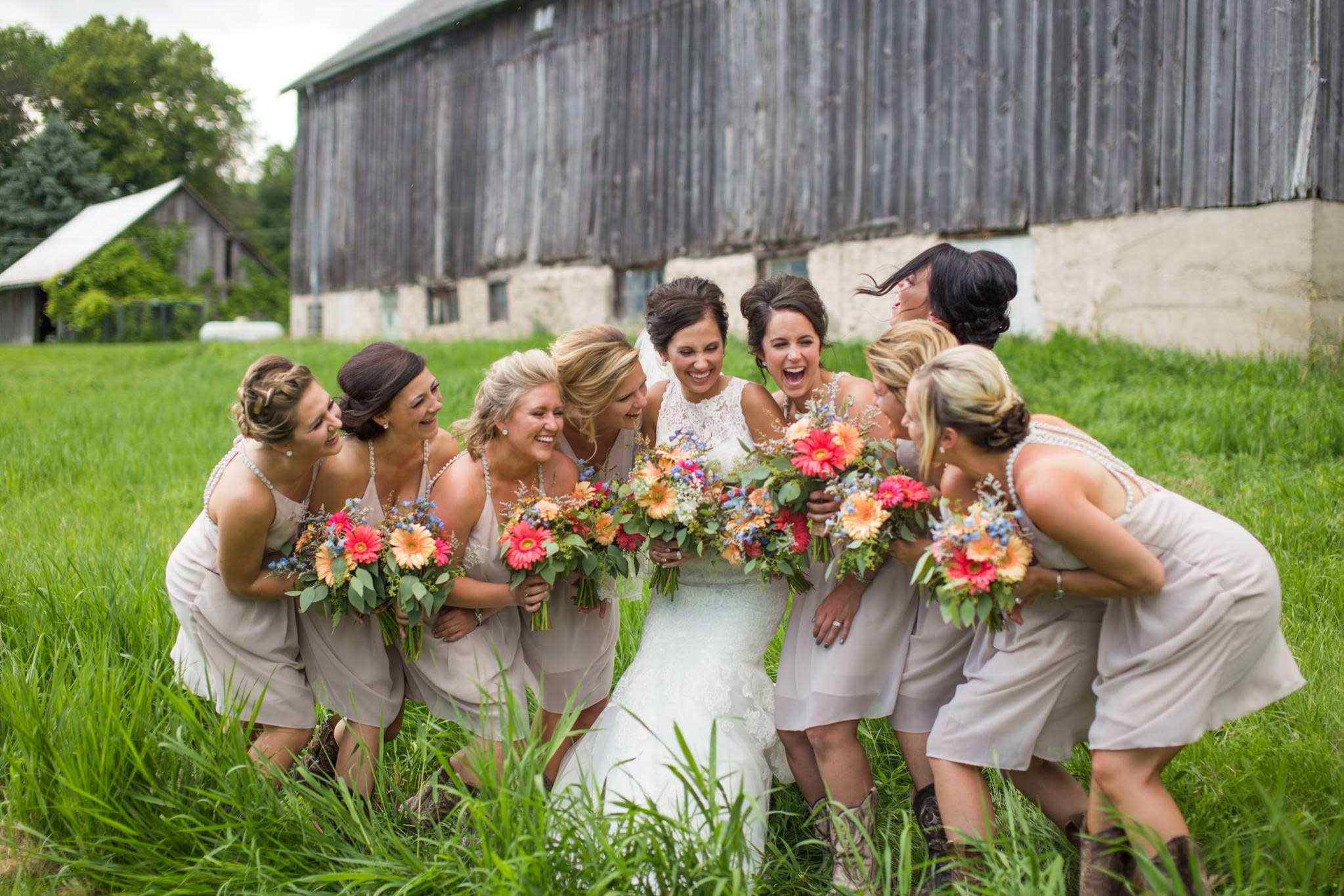 Bride and bridesmaids holding bouquets outside rustic Omaha barn venue