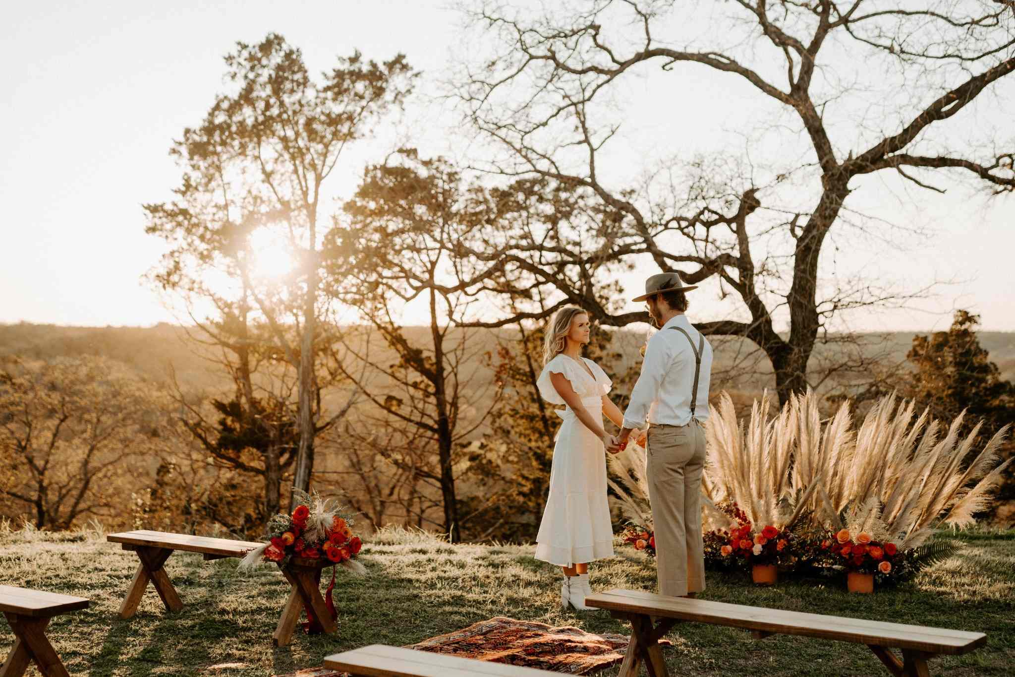 Rustic outdoor Texas wedding ceremony with wooden benches and expansive rolling hill views