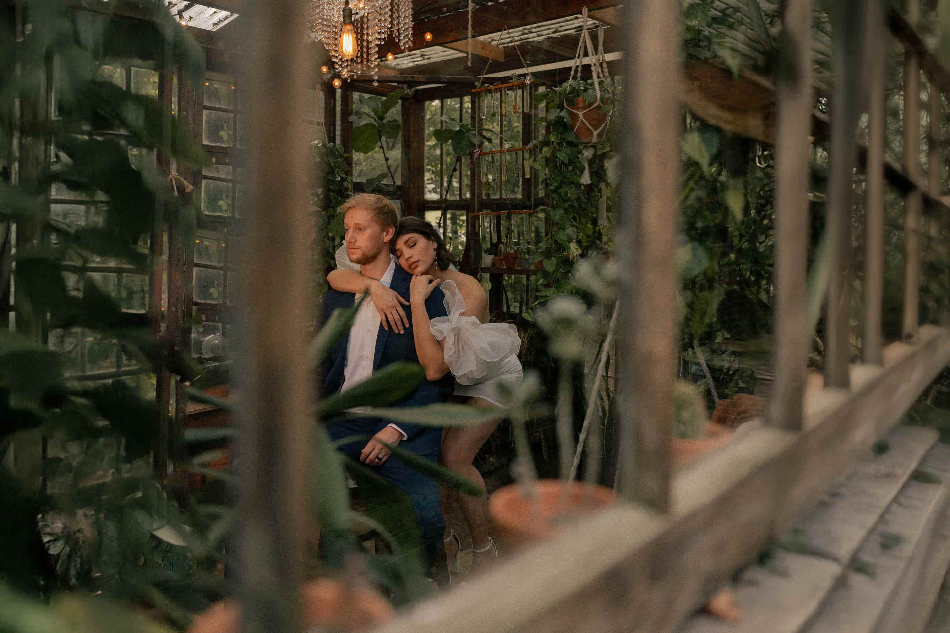 Couple seated in a lush, plant-filled conservatory venue perfect for Maryland events