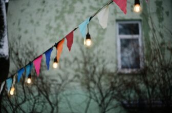 A beautifully decorated outdoor space for an event, featuring simple yet elegant decorations like string lights, table settings, and greenery.